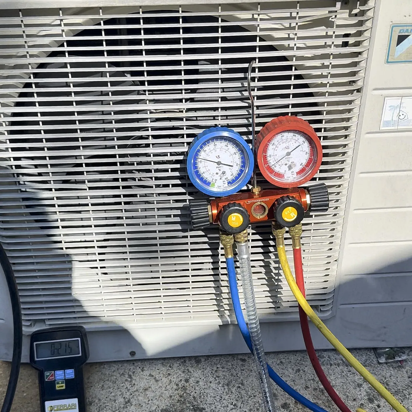 Gruppo manometrico collegato all'unità esterna di un climatizzatore Daikin, con la bilancia per la carica del gas refrigerante