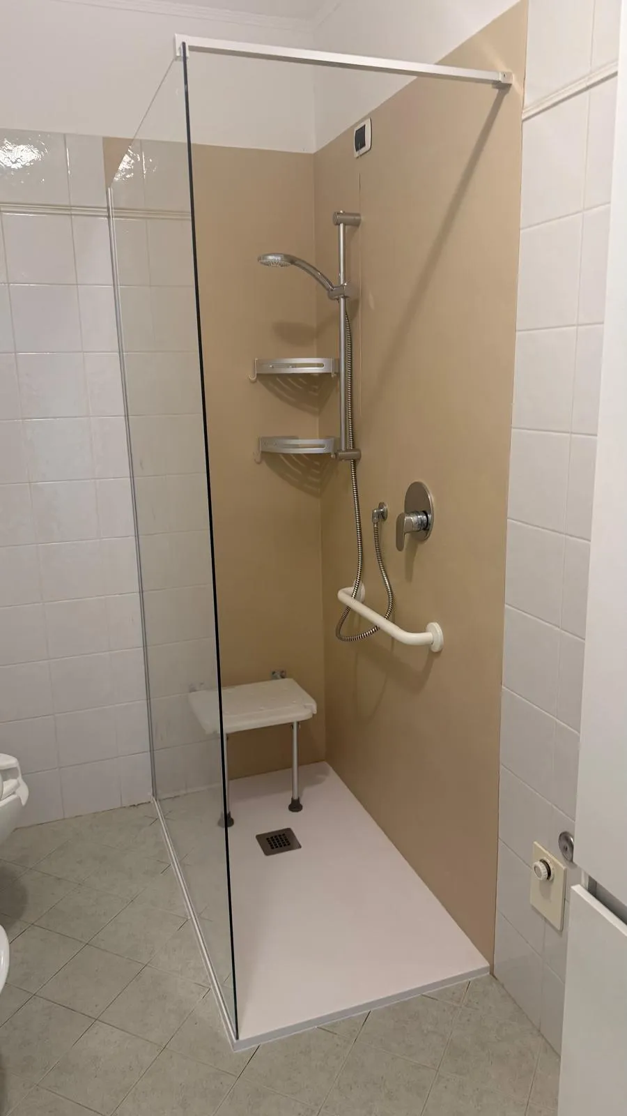 Doccia accessibile completata con rivestimento in resina, maniglioni di sostegno e dispositivi di sicurezza, progettata per garantire comfort, autonomia e facilità di utilizzo.