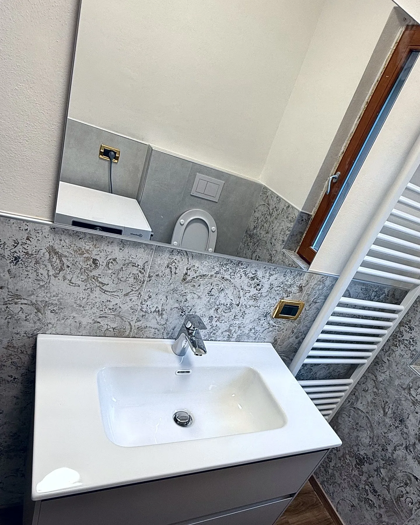 Mobile lavabo sospeso dalle linee moderne, con ampio piano in ceramica, rubinetteria cromata e specchiera di grandi dimensioni. Una composizione elegante e funzionale.